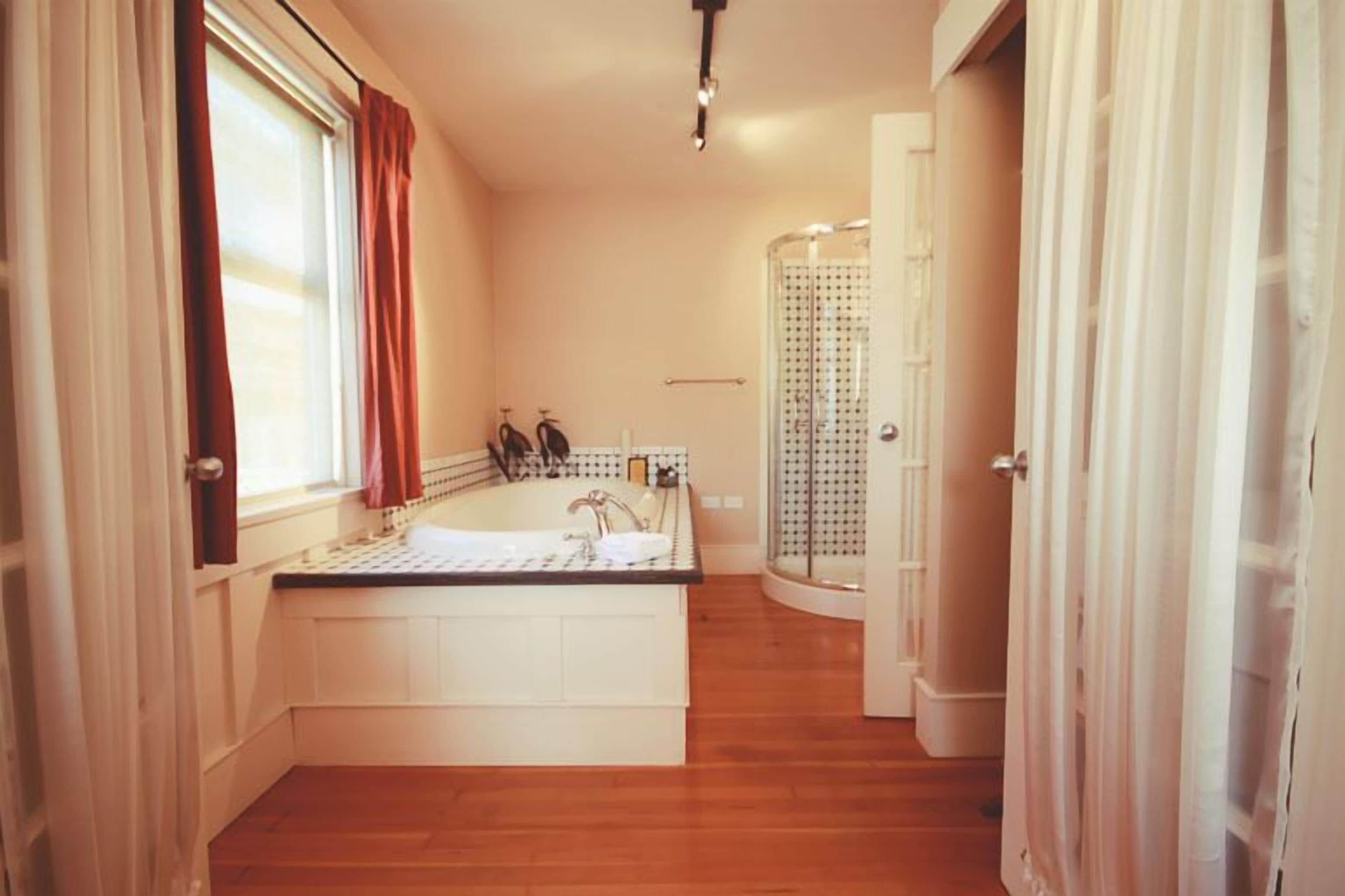 Une salle de bain avec une baignoire, une douche et une fenêtre avec des rideaux.