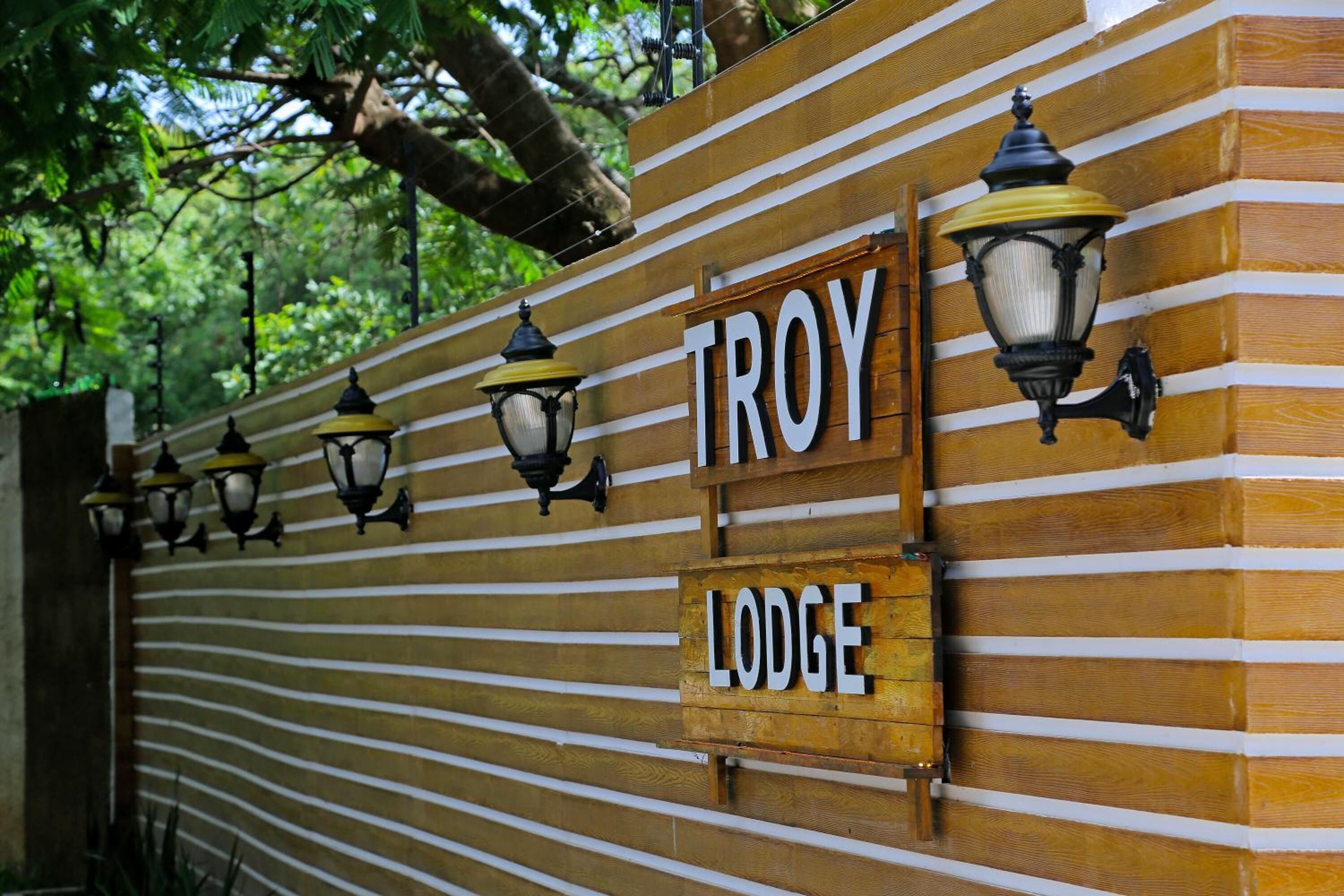 A wooden fence with the words "TROY LODGE" and decorative street lamps.