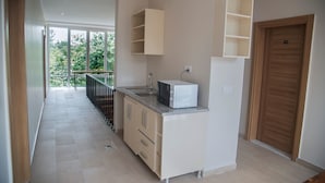 A modern kitchen with a built-in microwave, a sink, and a wooden door. - Troy Serviced Apartments (Lusaka)
