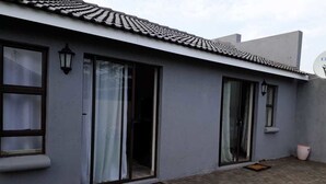 A modern building with large sliding glass doors, a satellite dish, and a satellite dish on the roof. - Carnival View Guest house (Boksburg)