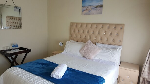 A neatly made bed with a blue blanket, white pillows, and a beige headboard. - Carnival View Guest house (Boksburg)