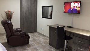 A room with a massage chair, a desk, a television, and a cabinet. - Carnival View Guest house (Boksburg)