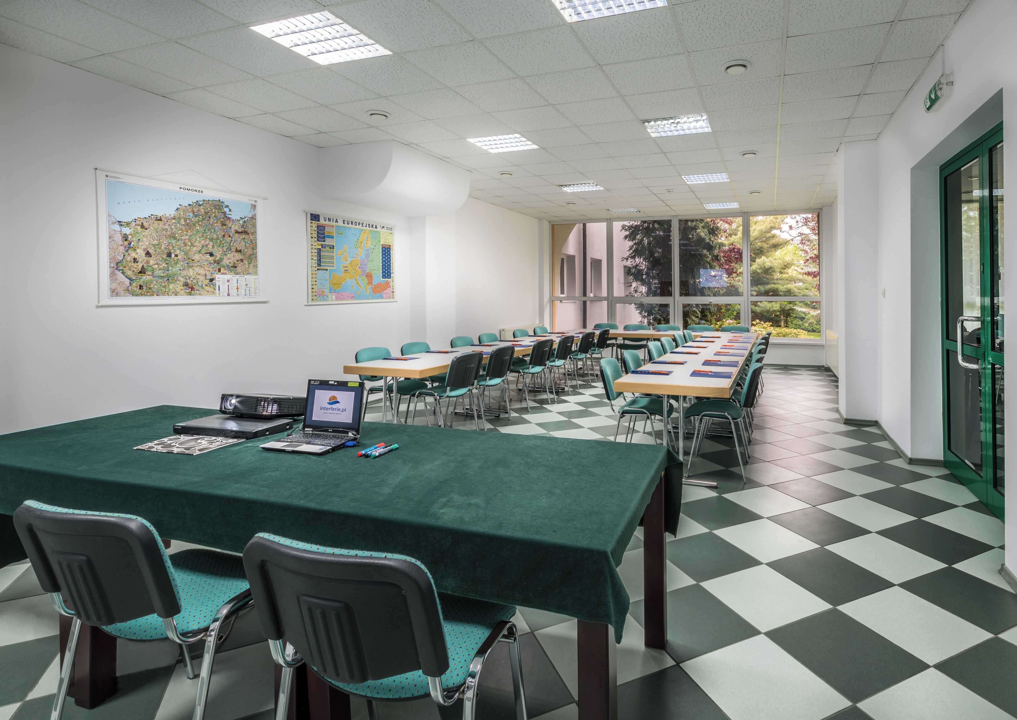 A conference room with a long table, chairs, a projector, and a laptop.