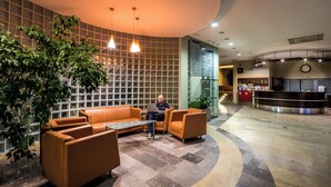 Un hall con mostrador de recepción, zona de estar y pared con diseño de cuadrícula.