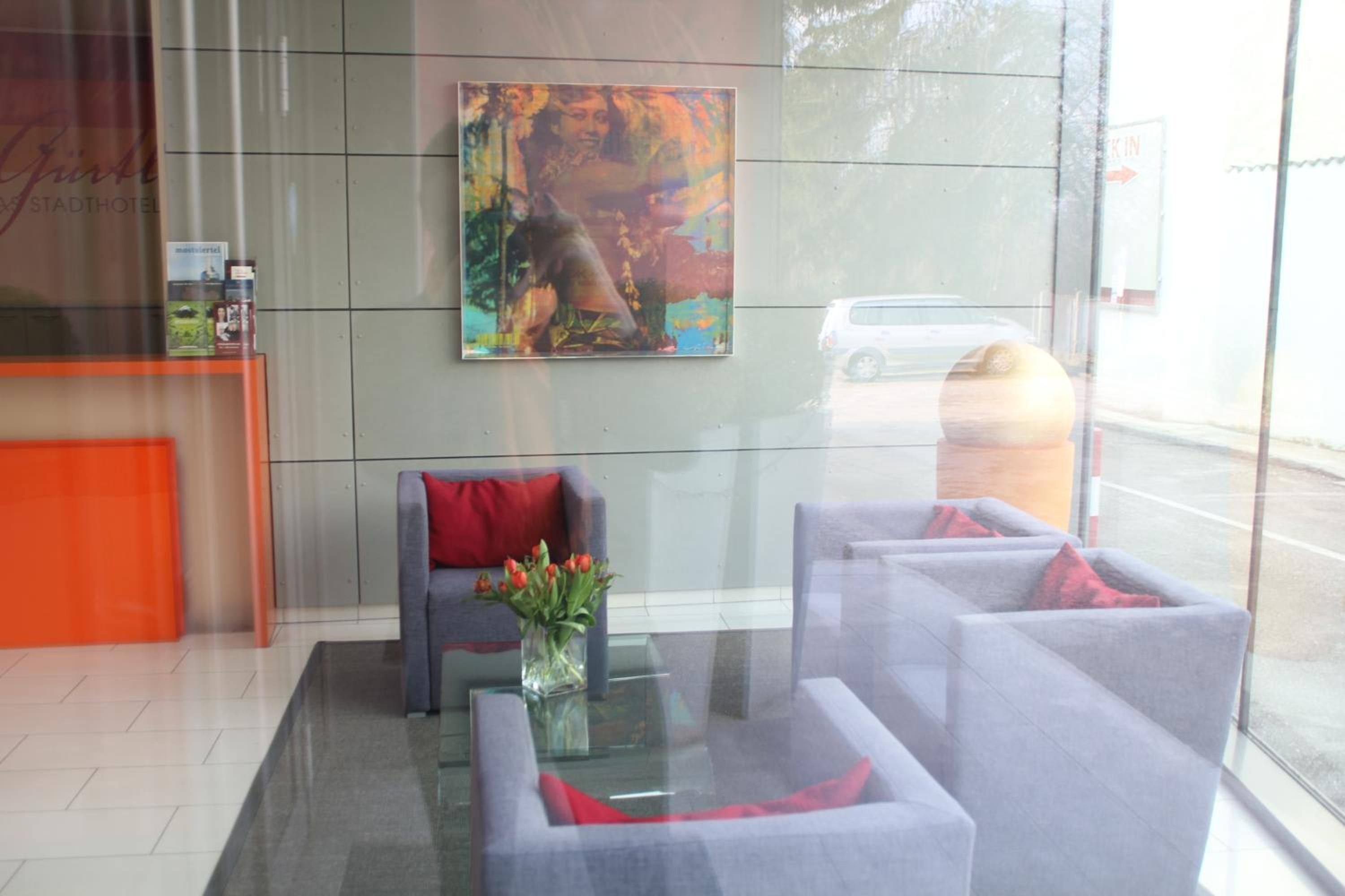 A modern lobby with a reception desk, seating area, and a large window.