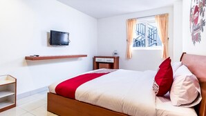A hotel room with a bed, a TV mounted on the wall, a window with curtains, and a small table with a bottle. - Stadthotel Gürtler (Amstetten)