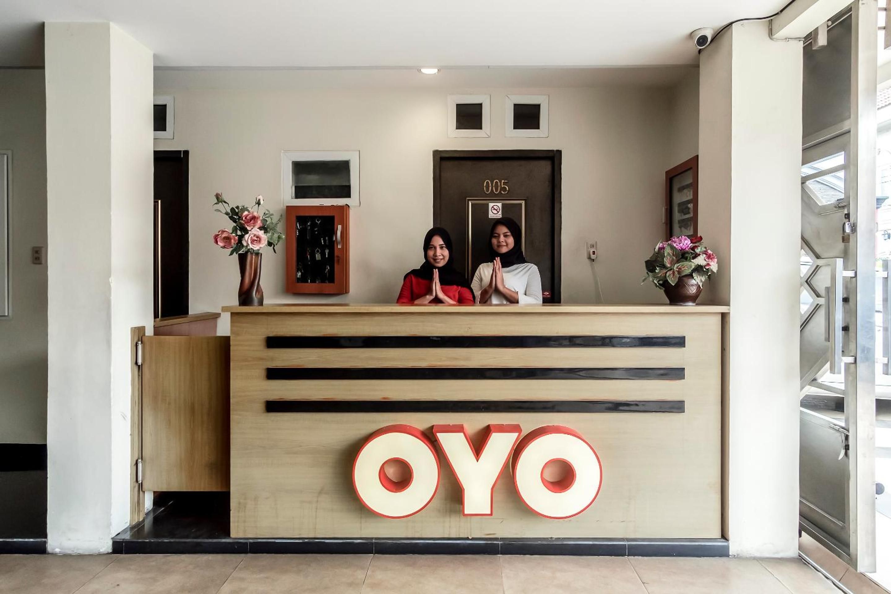 Ein Empfangsschalter mit einem großen 'OYO'-Logo, eine Tür mit einer Nummer und eine Überwachungskamera.