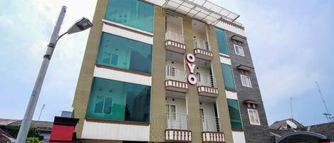 Un edificio de varios pisos con un llamativo letrero 'OYO', ventanas grandes y un balcón en los pisos superiores.