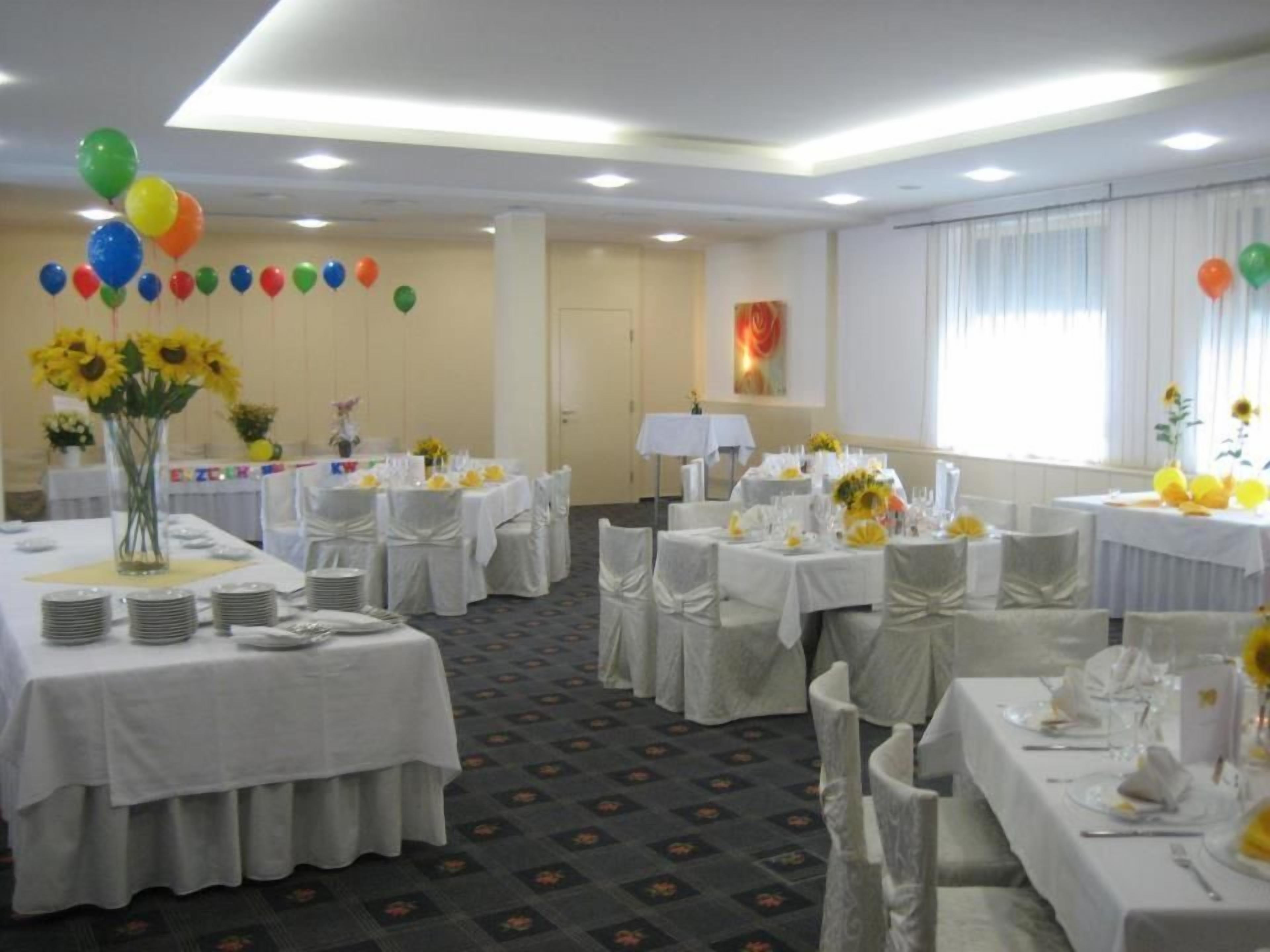 Ein Festsaal mit runden Tischen, weißen Tischdecken und Sonnenblumen.