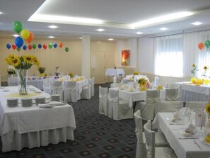 A banquet hall with round tables, white tablecloths, and sunflowers.