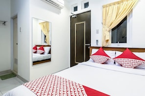 Una habitación de hotel con una cama, un armario, un espejo y una ventana con cortinas.