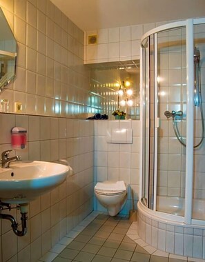A bathroom with a sink, toilet, and glass-enclosed shower. - Klosterhof (Wehr)