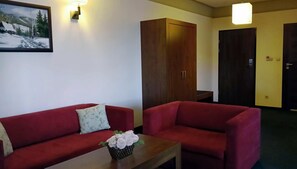 A room with a red sofa, a wooden cabinet, and a painting on the wall. - Ahotel (Czechowice-Dziedzice)