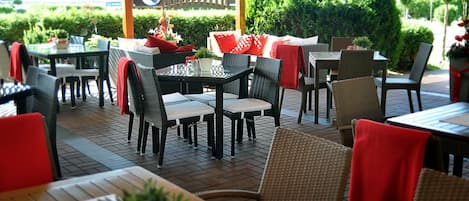 Un espace extérieur aménagé pour les repas, avec des meubles en osier, des tables et des chaises.