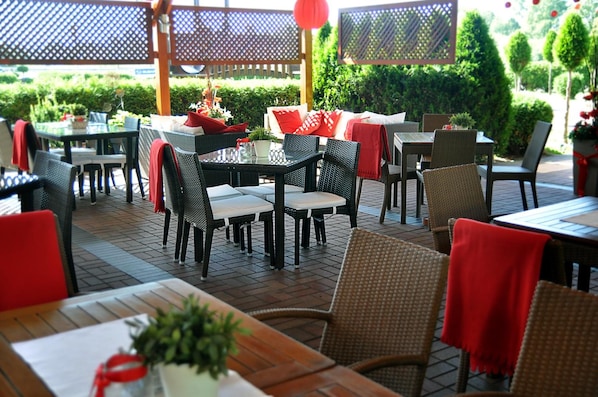An outdoor dining area with wicker furniture, tables, and chairs.