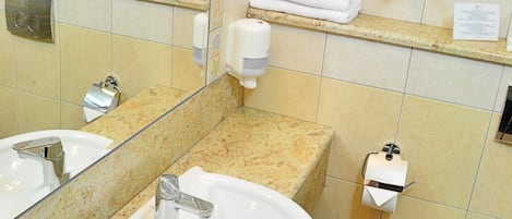 A bathroom with a sink, mirror, towel rack, and toilet.