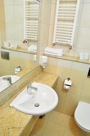 A bathroom with a sink, mirror, towel rack, and toilet.