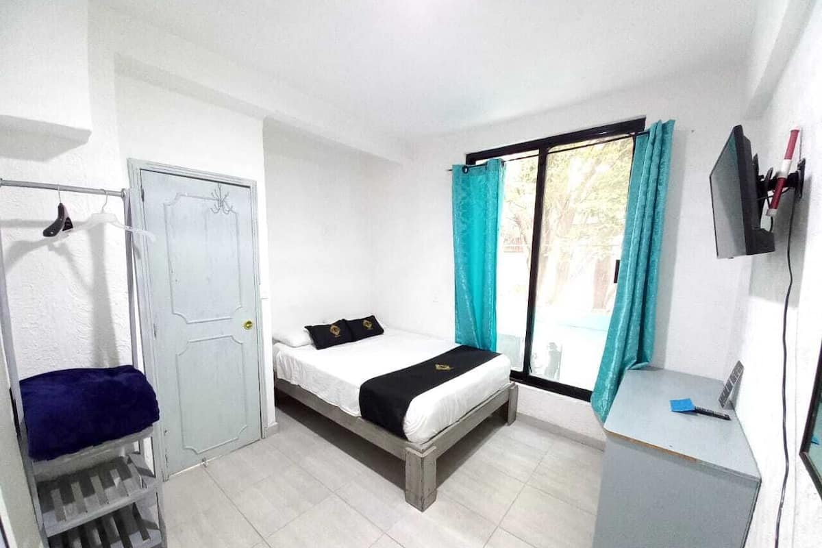 A compact room with a bed, a desk, and a wardrobe.