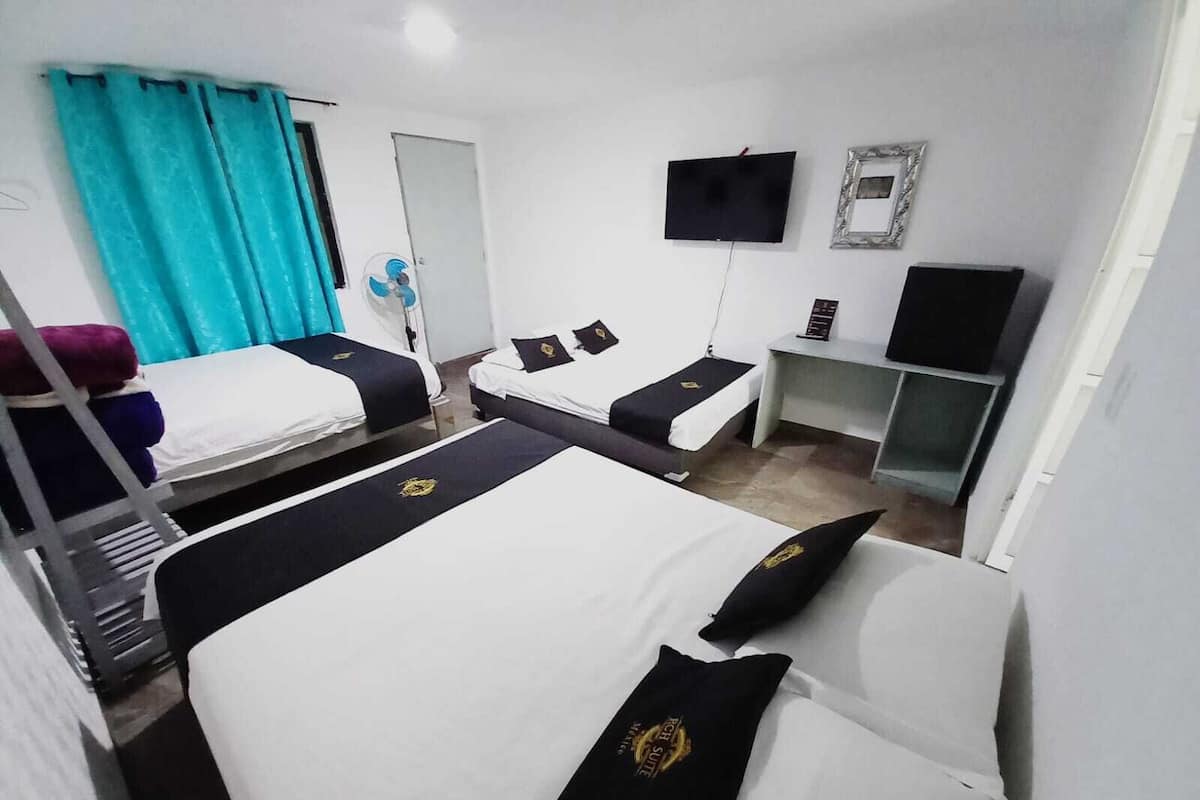 A hotel room with two beds, a TV, a desk, and a mirror.