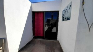 A narrow hallway with a red curtain, a tiled floor, and a door leading to a balcony. - RCH Suite (Mexico City)