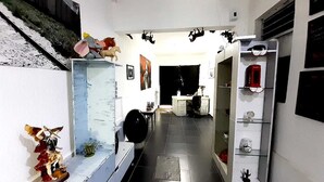 A hallway with a staircase, a desk with a computer, and shelves with various items. - RCH Suite (Mexico City)