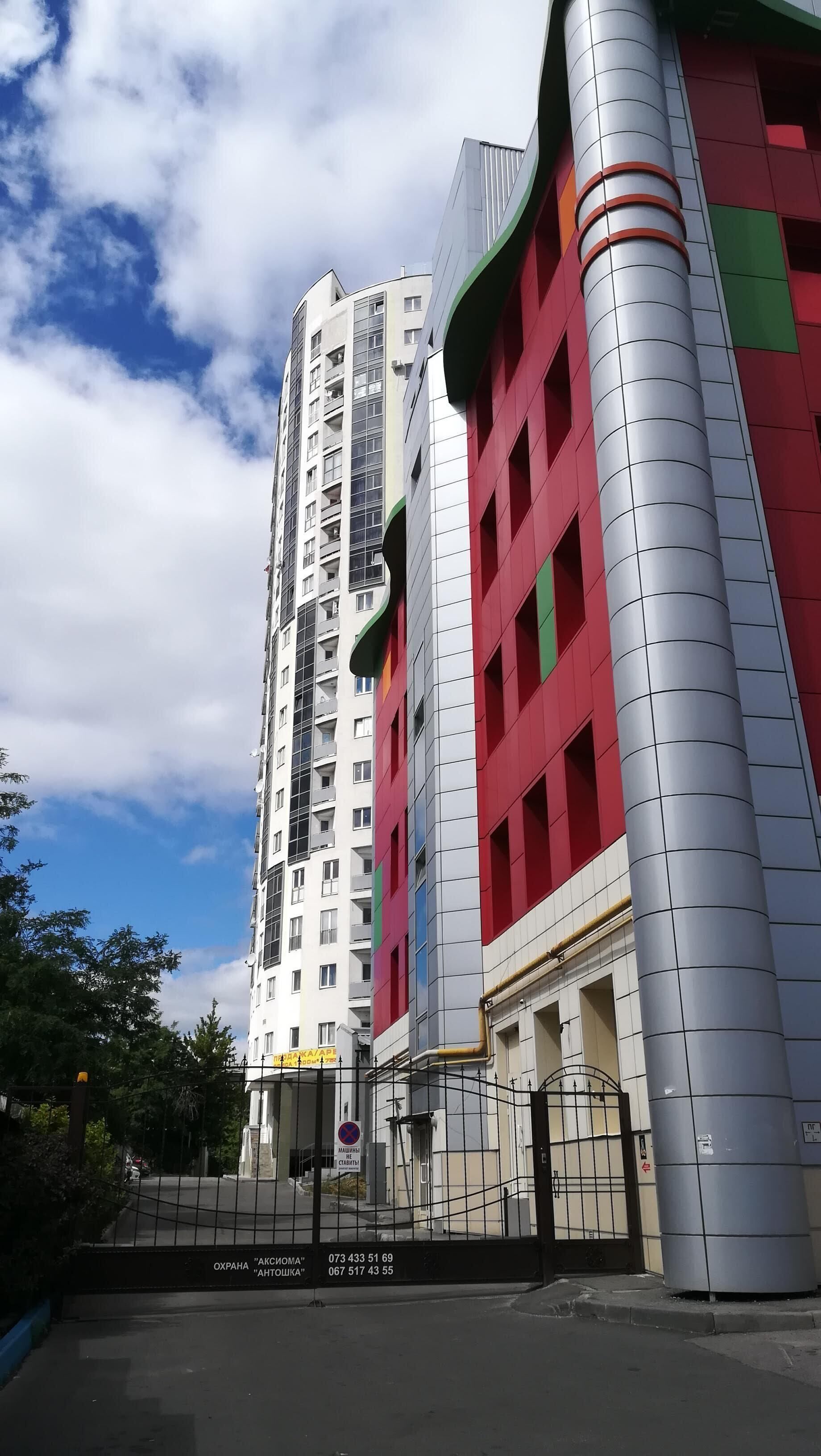 Un edificio de varios pisos con un diseño arquitectónico moderno, que presenta una combinación de fachadas blancas y de colores.