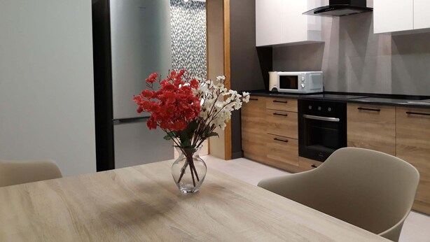 A modern kitchen with a refrigerator, microwave, and wooden cabinets.