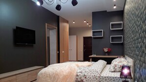 A modern bedroom with a bed, bedside table, and a TV on the wall.