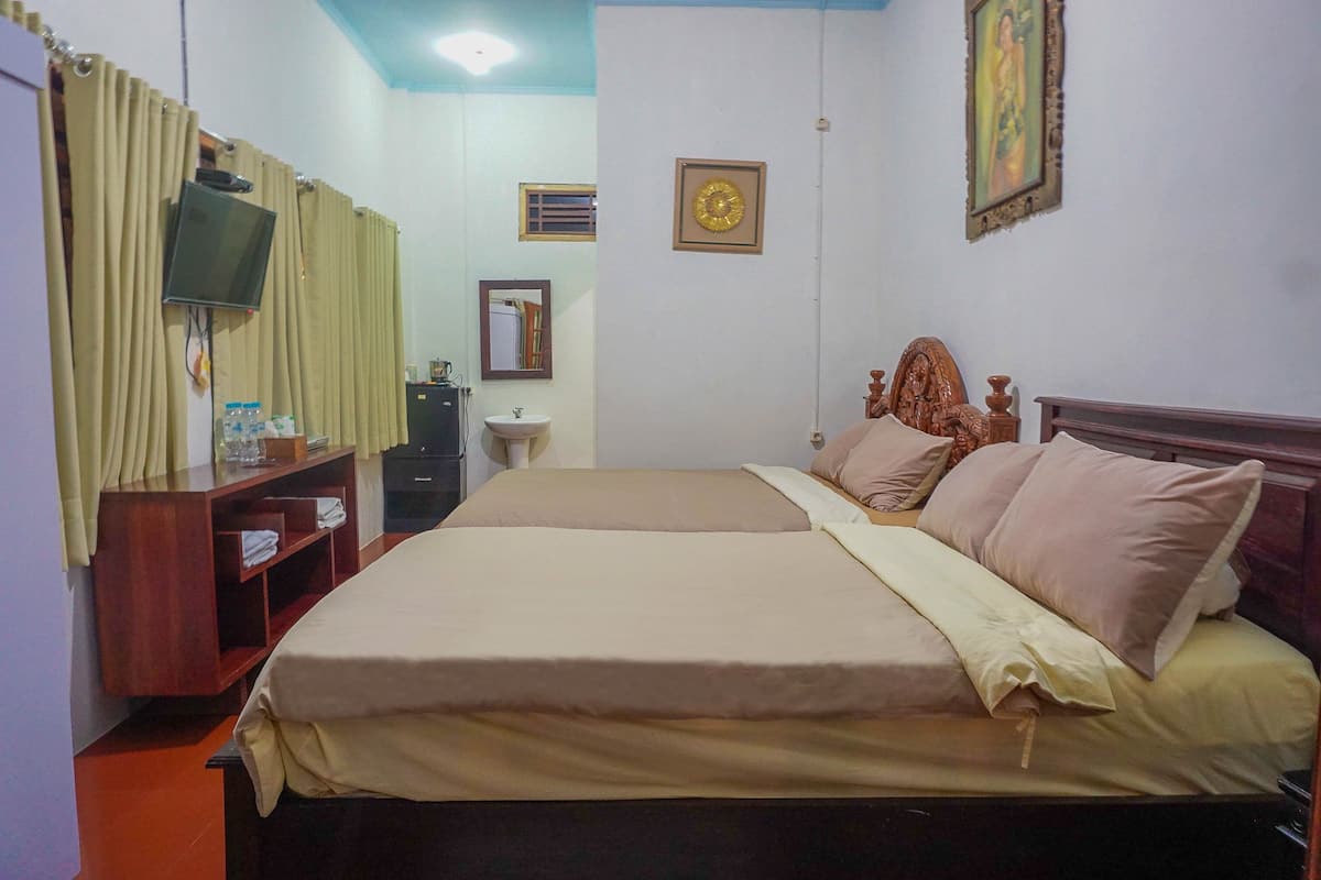 A hotel room with a bed, a television, a mirror, a clock, and a small shelf.