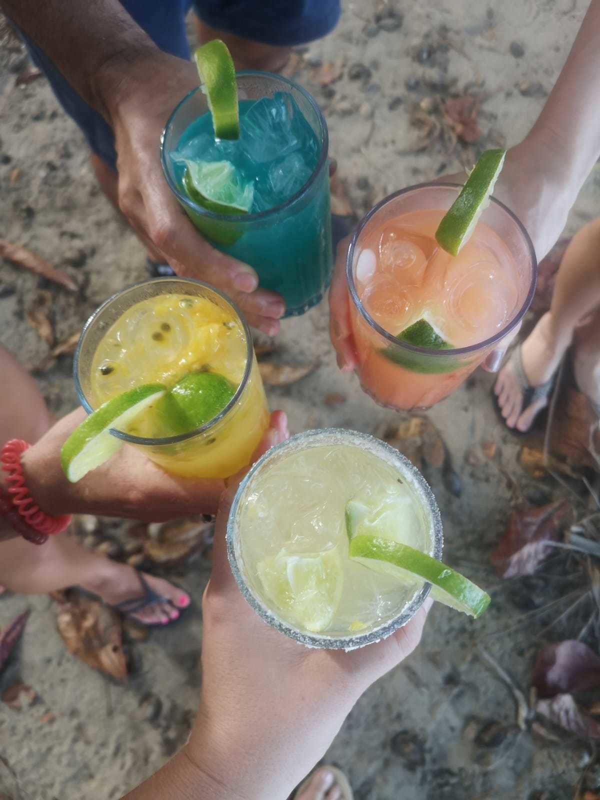 Tres personas sosteniendo bebidas con rodajas de lima.