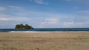 A beach with a small island in the distance. - Tasty Dayz Hostel (Cahuita)
