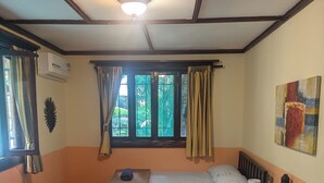 A hotel room with two beds, a ceiling fan, an air conditioning unit, a window with curtains, and a painting on the wall. - Tasty Dayz Hostel (Cahuita)