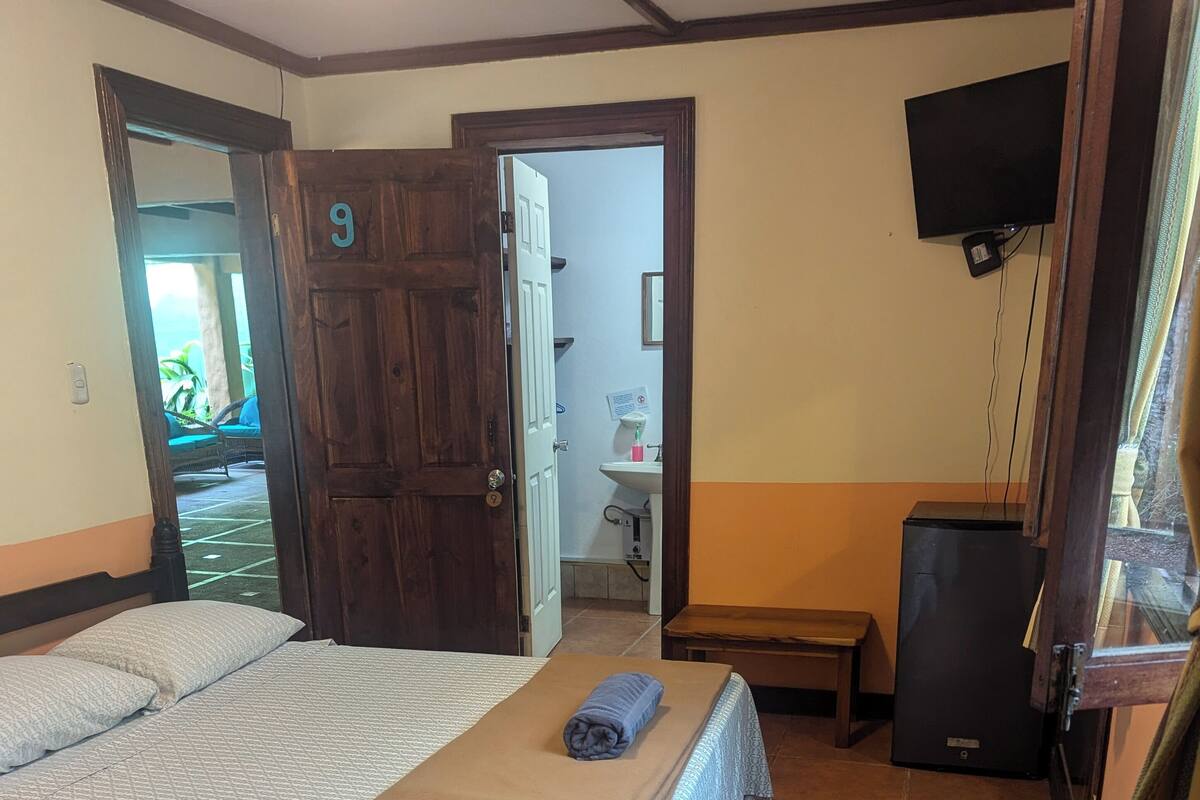 A room with two beds, a wooden door, a television, and a small table.