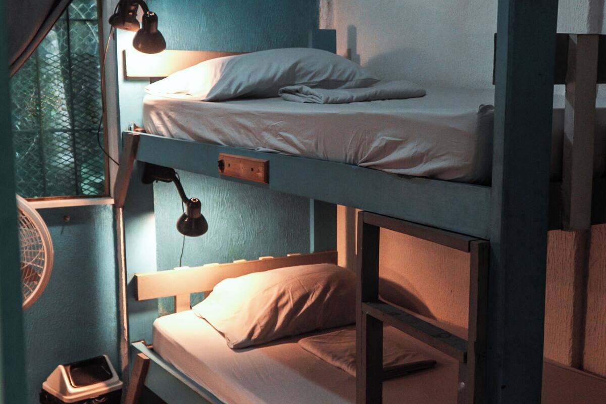 A bunk bed room with a window, a desk, and a chair.