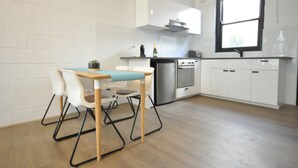 Una cocina moderna con armarios blancos, una mesa de madera y un ventanal.