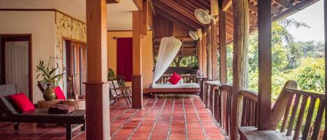 Un espacio exterior cubierto con suelo de baldosas, muebles de madera y una cama con dosel.