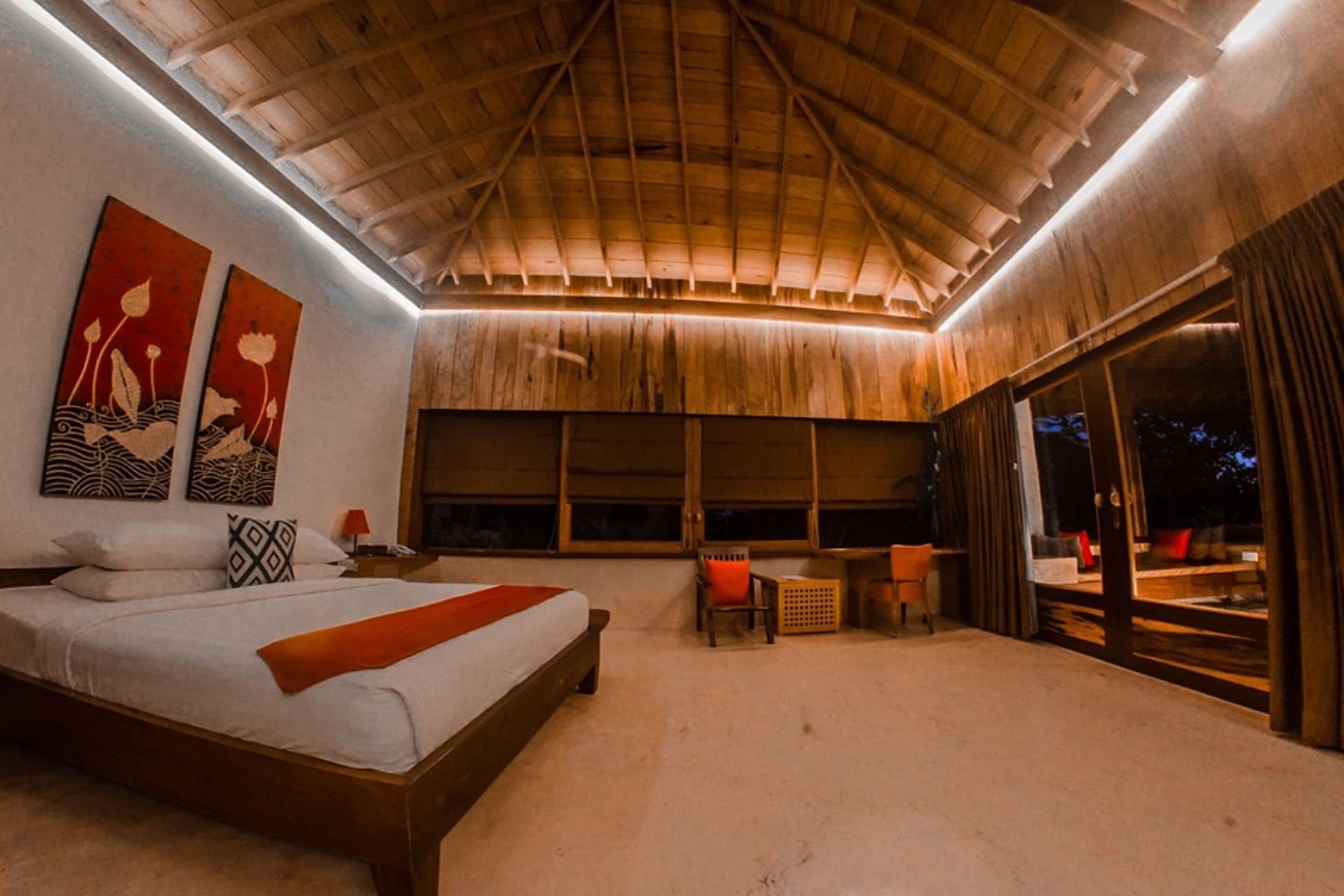 Un dormitorio con una cama grande, techo de madera y vistas a través de un ventanal.