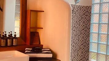 Un baño con tocador de madera, ducha con mosaicos y ventana con vistas.