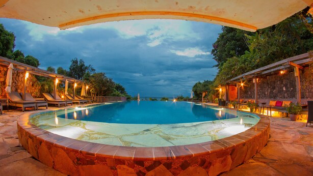 Una piscina circular infinita con borde de piedra, rodeada de sillones de descanso y una zona de estar cubierta.