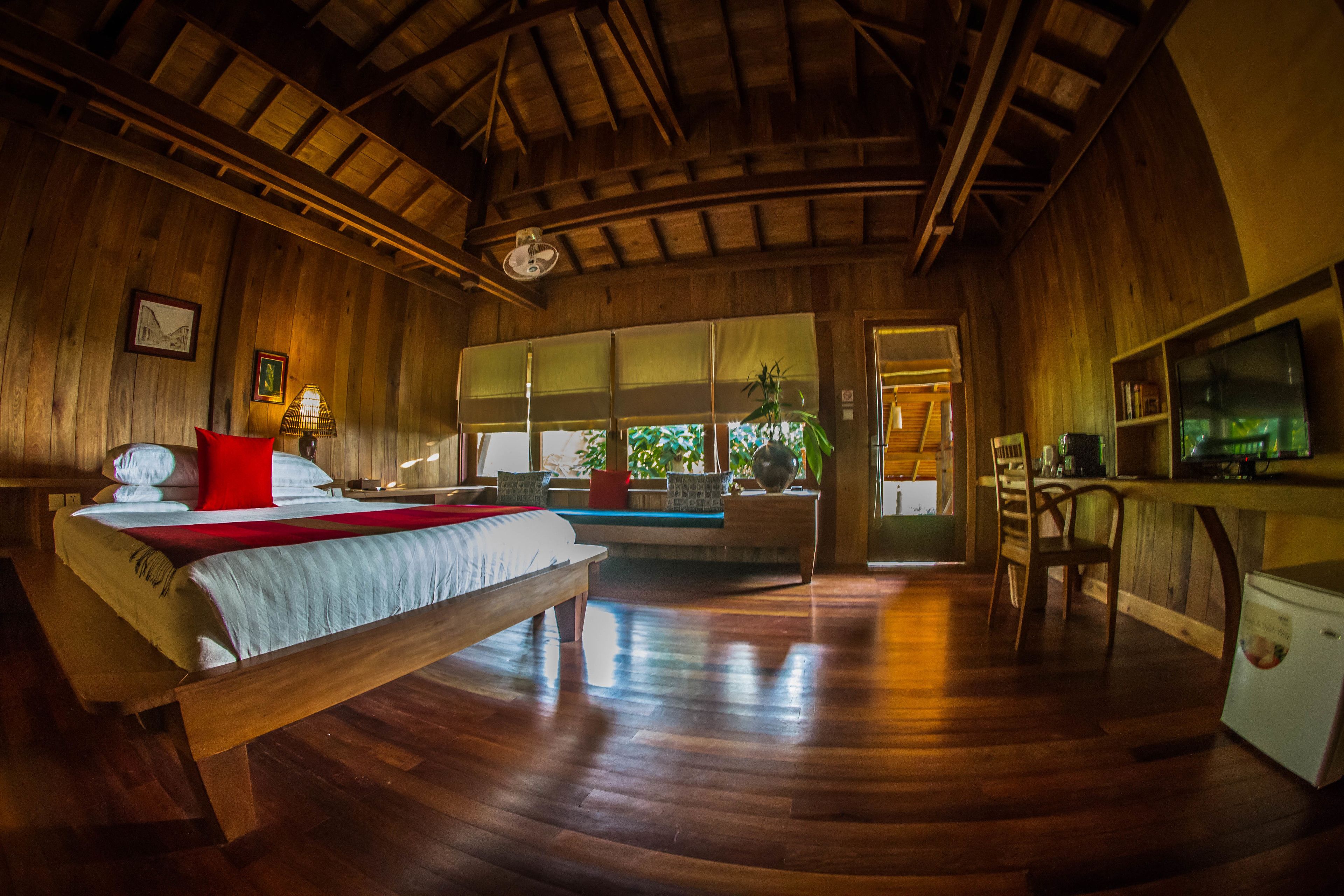 Una habitación de madera con una cama, un escritorio y un televisor.