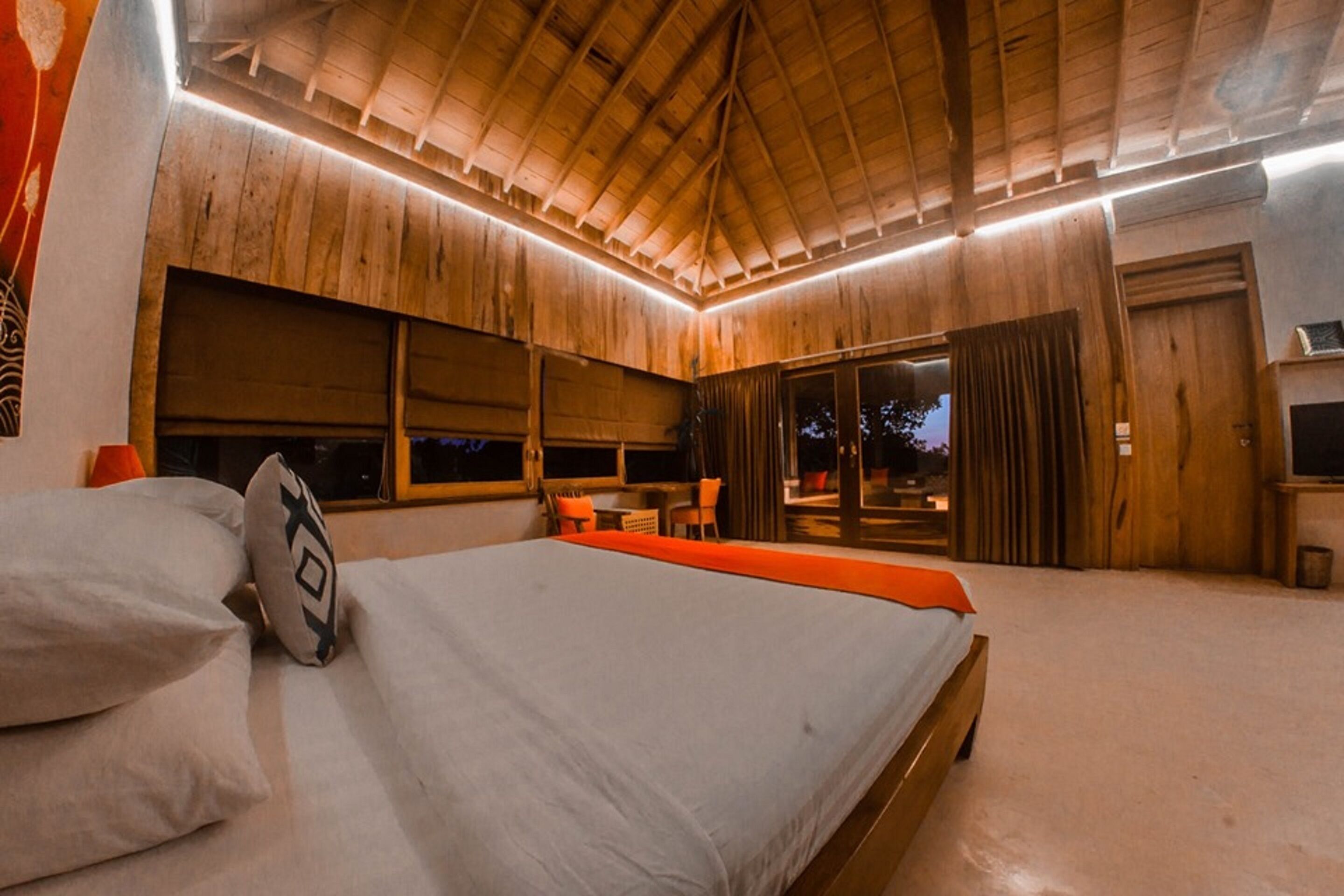 Une chambre avec un plafond en bois, un lit avec des oreillers, une télévision et une fenêtre avec des rideaux.