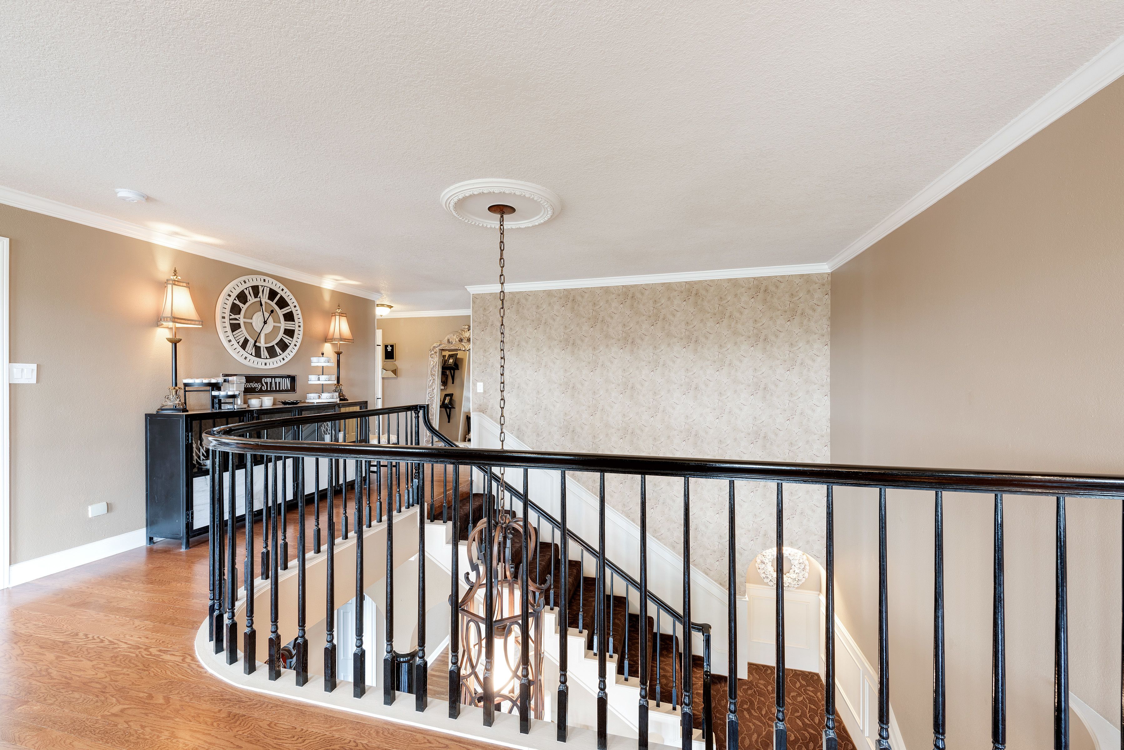 A spacious living area with a curved staircase, a decorative clock, and a chandelier.