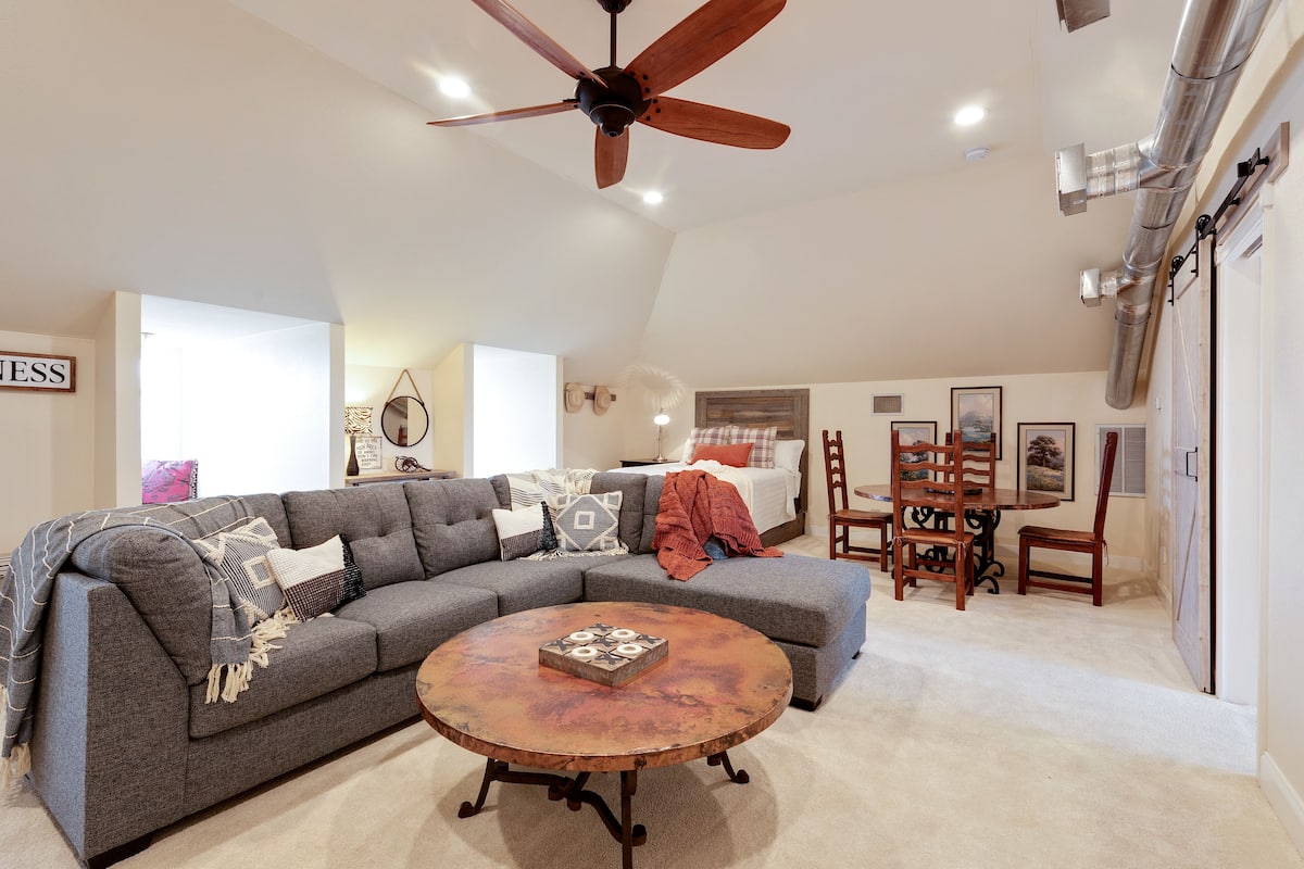 A living room with a sectional sofa, a round coffee table, a ceiling fan, and a dining area with chairs and a table.