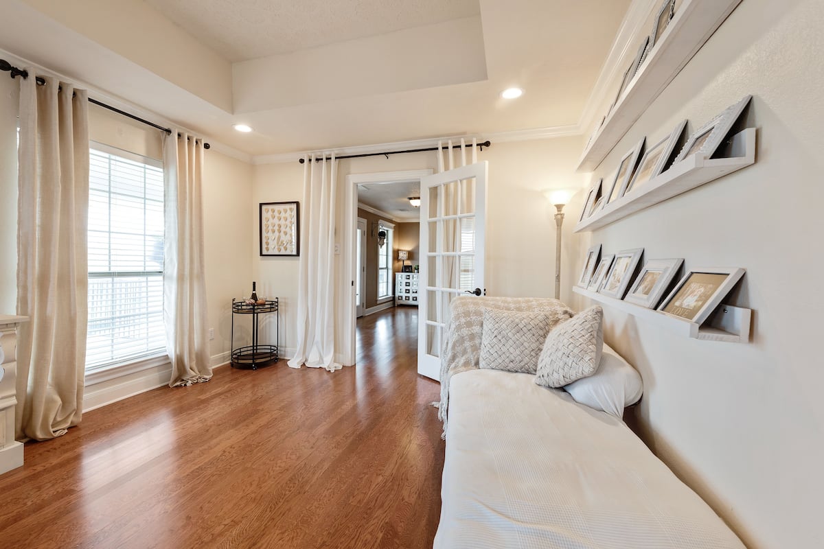 A spacious living room with hardwood flooring, a white sofa, and a gallery wall of framed pictures.