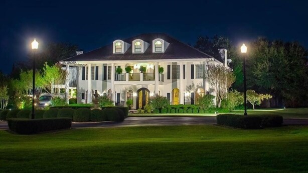 A large, two-story house with a symmetrical facade, multiple windows, and a central entrance.