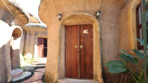 Un bâtiment rustique avec une porte en bois, des marches en pierre et des plantes en pot.