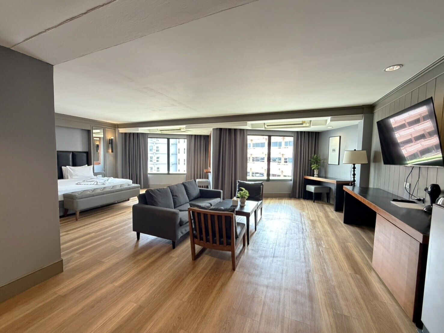 A hotel room with a bed, sofa, desk, and TV.