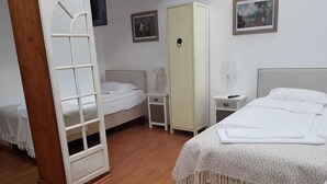 Une chambre avec deux lits, une armoire, une table de chevet avec une lampe et une petite chaise.
