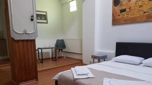 Une chambre d’hôtel avec un lit, une chaise, une petite table et un radiateur.