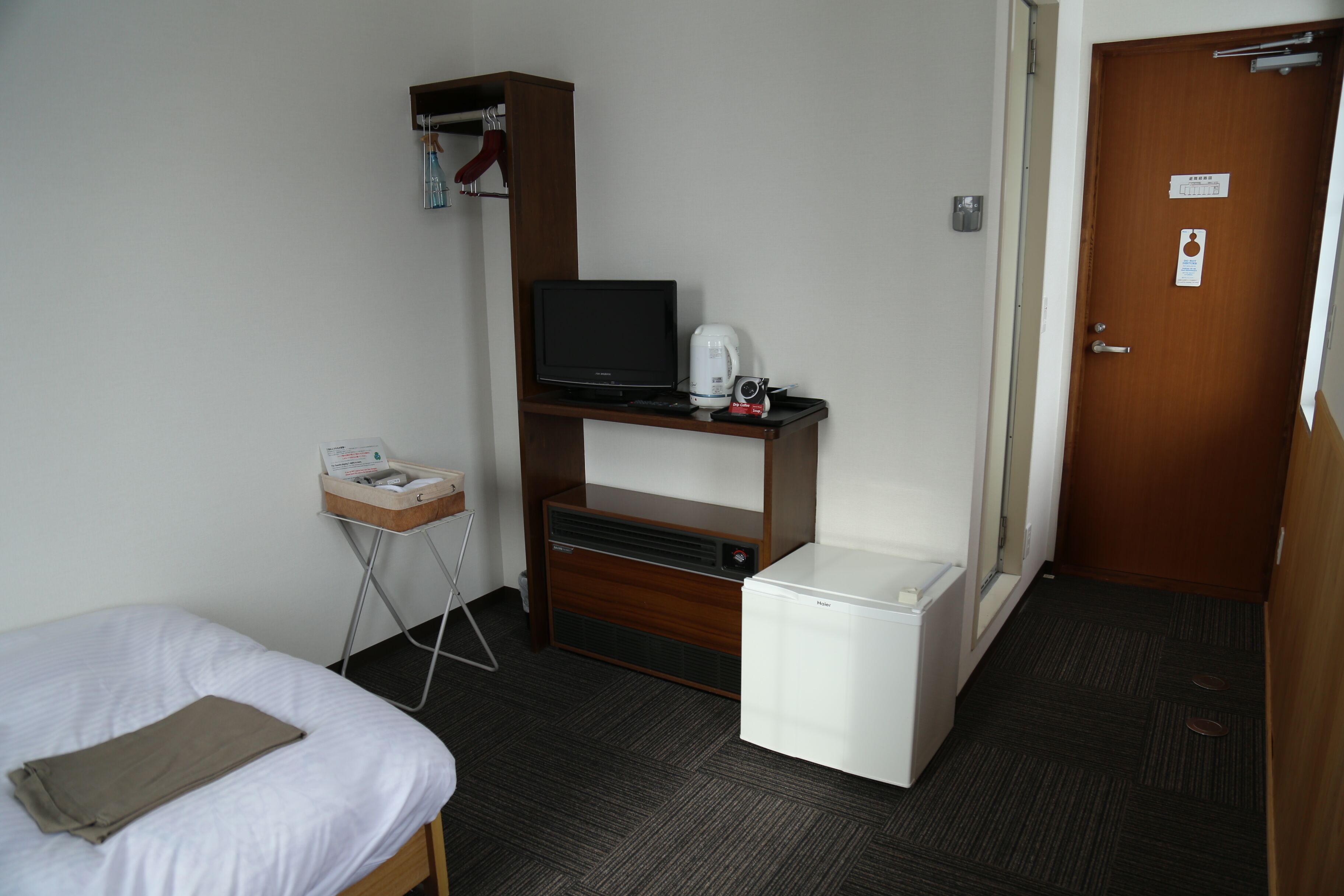 Une chambre d’hôtel comprenant un lit, un petit bureau avec une télévision, un mini-réfrigérateur et une petite kitchenette.
